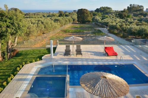 uma piscina com guarda-sol, cadeiras e mesas em Villa Zeas em Halikounas