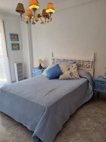 a bedroom with a bed with blue pillows and a chandelier at COSTA DAURADA APARTAMENTS - 174 Formentor Luxe II in Salou