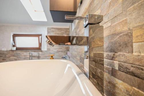 une baignoire dans une salle de bain avec un mur en pierre dans l'établissement Lovely house in the most peacefull place of Grado, à Grado