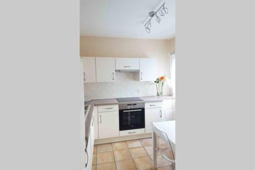 une petite cuisine avec des armoires blanches et une table dans l'établissement ARGELES-GAZOST - La Terrasse de l'Araillé, à Argelès-Gazost