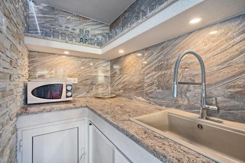a kitchen with a sink and a microwave at Apartments & Bungalows Ivanović in Kaštela