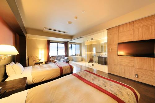 a hotel room with two beds and a flat screen tv at Tensui Saryo in Hakone
