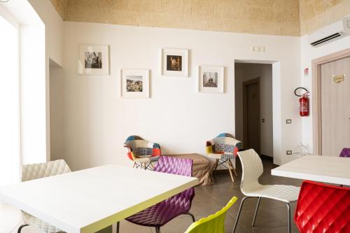 ein Esszimmer mit weißen Tischen und bunten Stühlen in der Unterkunft Nova Domus in Castellaneta