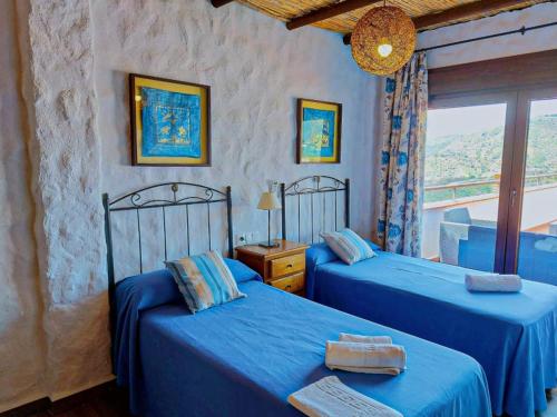 1 dormitorio con 2 camas azules y ventana en Villa Sara y Villa Lucía, en Canillas de Albaida