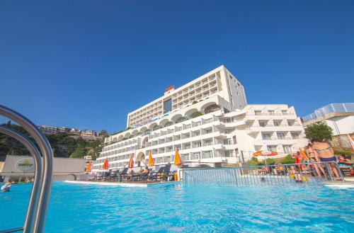 a hotel with a swimming pool in front of a building at Hotel Sunce in Neum