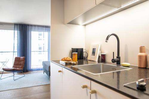 eine Küche mit einem Waschbecken und ein Wohnzimmer in der Unterkunft ipartment Böblingen Region Stuttgart in Böblingen