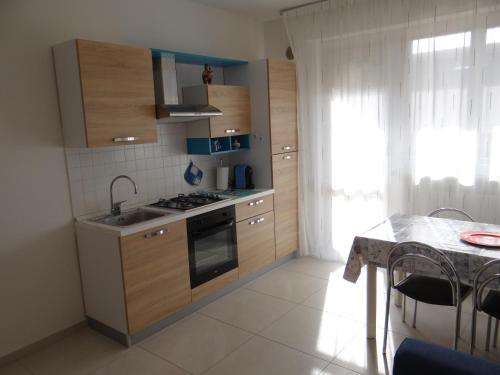 eine Küche mit Holzschränken, einer Spüle und einem Tisch in der Unterkunft Luminoso Appartamento al mare in Martinsicuro