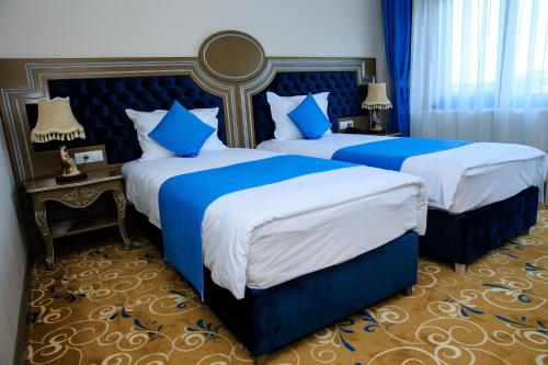 duas camas num quarto de hotel com azul e branco em La Casa cu Stuf em Baldovineşti