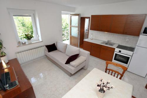 a living room with a white couch and a kitchen at Apartment Gorgo in Sečovlje