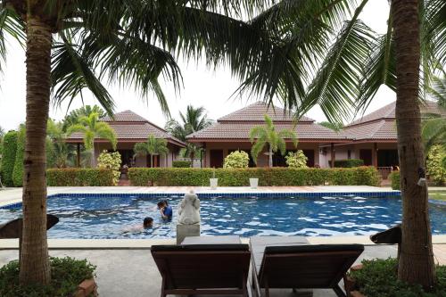 a swimming pool with a statue in front of a house at Waterside Resort in Pran Buri