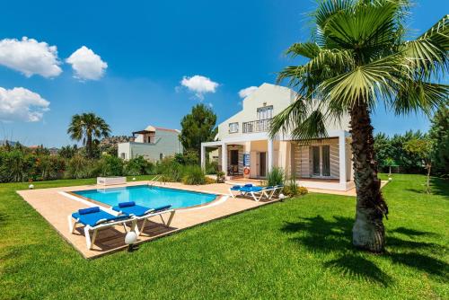 a villa with a swimming pool and a palm tree at Apollo Villa in Kolymbia