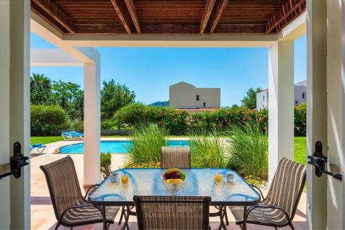 een terras met een tafel en stoelen en een zwembad bij Apollo Villa in Kolimbia