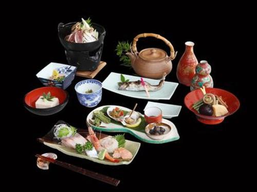 una mesa con platos de comida y una tetera en Ryokan Dangoya, en Kamiichi