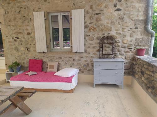 a bedroom with a bed and a dresser and a stone wall at La Maison du Chassezac in Les Assions