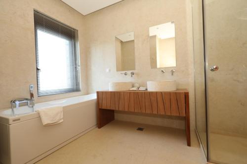 a bathroom with a tub and a sink and a mirror at Luxury Villa Veronika in Pláka