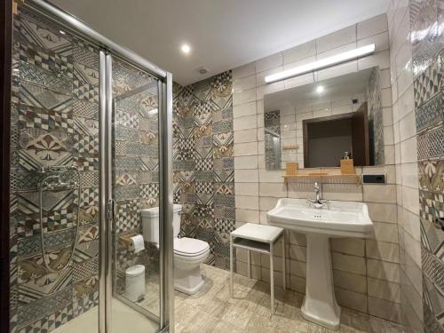 a bathroom with a toilet and a sink and a shower at APARTAMENTOS RURALES POSADA DE LLERENA in Llerena