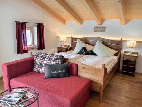1 dormitorio con 1 cama y 1 sofá rojo en Holiday Home Haus Seitner - BMG160 by Interhome, en Mühlbach