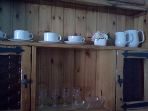 a wooden shelf with cups and wine glasses on it at B&B Trento Nord in Trento