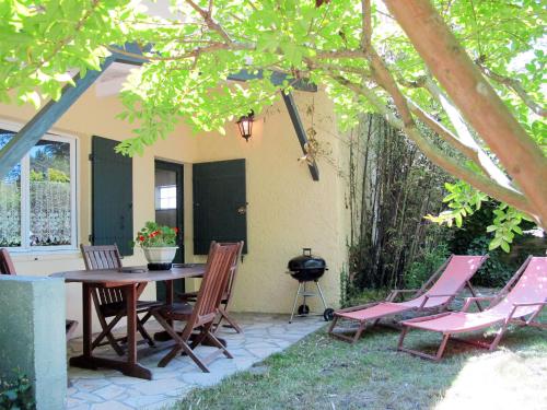 a patio with a table and chairs and a grill at Holiday Home Les Sables - QUE100 by Interhome in Queyrac