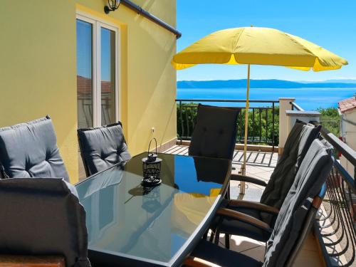 d'une table en verre avec des chaises et un parasol sur le balcon. dans l'établissement Apartment Marinella - LBN121 by Interhome, à Labin
