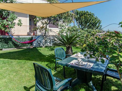 a table and chairs in a yard with an umbrella at Apartment Etna View by Interhome in Mascali