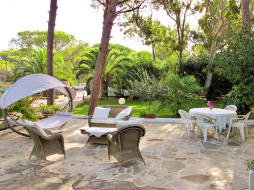 a patio with white tables and chairs and trees at Holiday Home Villa Margherita by Interhome in Platamona