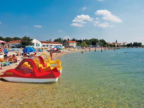 a beach with people and a boat in the water at Apartment Pusa by Interhome in Sveti Filip i Jakov