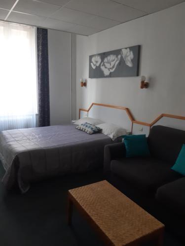 a hotel room with a bed and a couch at Hôtel de La Croix de Malte in Cherbourg en Cotentin