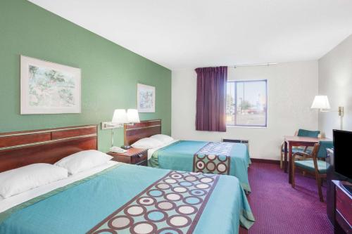 a hotel room with two beds and a desk at Super 8 by Wyndham Kennett in Kennett