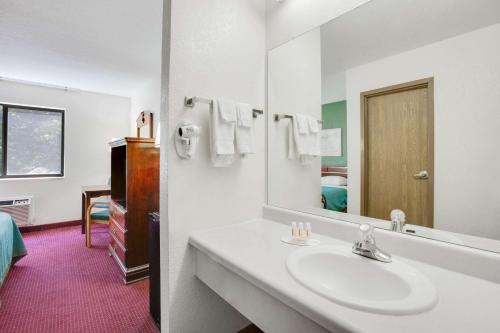 W białej łazience znajduje się umywalka i lustro. w obiekcie Super 8 by Wyndham Kennett w mieście Kennett