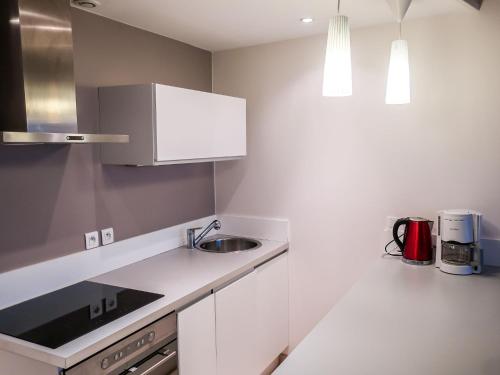 Apartment Les Deux voiles-1 by Interhome في La Foux: مطبخ فيه دواليب بيضاء ومغسلة