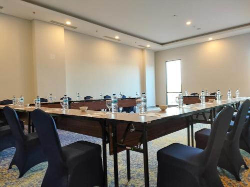 Suni Hotel and Convention Abepura managed by Parkside في Tobadi: قاعة اجتماعات كبيرة مع طاولة وكراسي طويلة