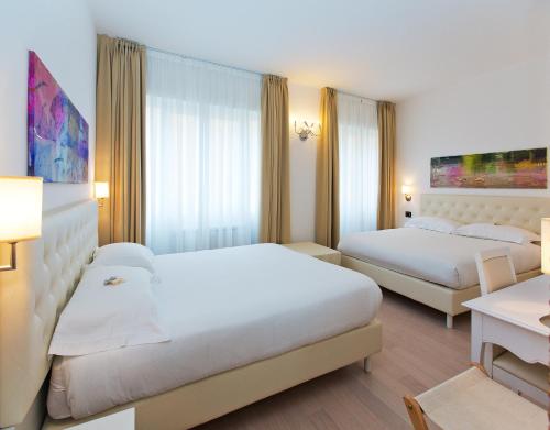 a hotel room with two beds and a desk at Hotel Mainè in Finale Ligure
