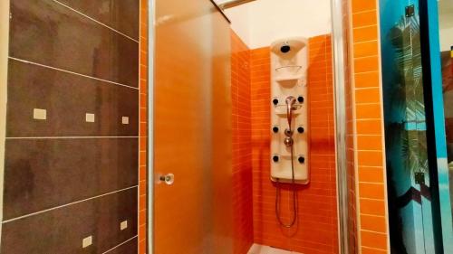 een douche in een badkamer met oranje tegels bij GialLobLu in Alghero