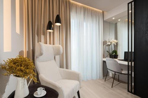 a living room with a white chair and a desk at Ivis 4 Boutique Hotel in Athens