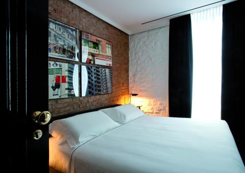 a bedroom with a white bed and a brick wall at Areadocks Boutique Hotel in Brescia
