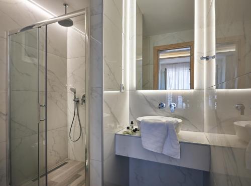 a bathroom with a shower and a sink and a mirror at Cactus Hotel in Laganas