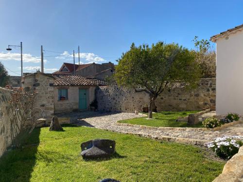 um quintal com uma casa de pedra e uma árvore em B&B Su Strintu em Tuili