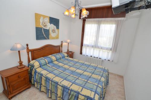 a bedroom with a bed with a blue and yellow blanket at Residencial Cilla - 6022 in Noja