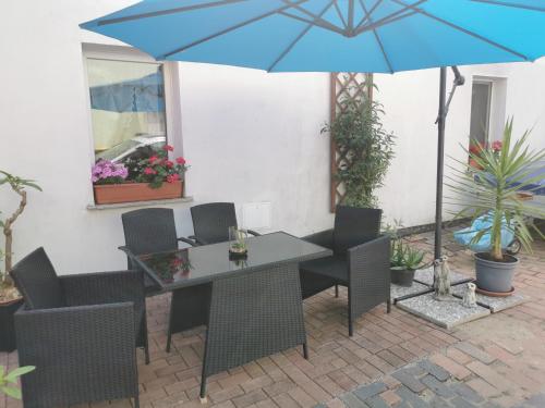 einen Tisch mit Stühlen und einen blauen Schirm auf einer Terrasse in der Unterkunft Vor den Toren Dresdens und der Oberlausitz in Radeberg