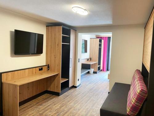 a living room with a tv and a room with a couch at first mountain Hotel Ötztal in Längenfeld