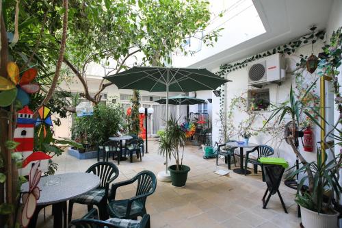 un patio con mesas, sillas y una sombrilla en Kallithea Studios, en Rethymno