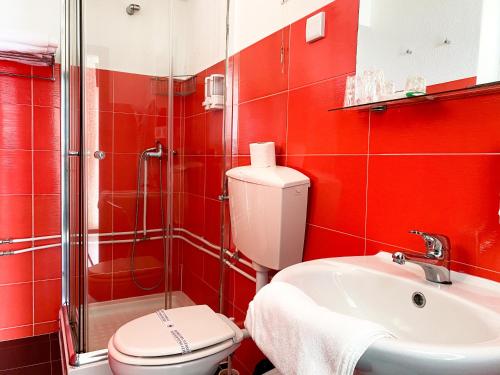 Baño rojo con aseo y lavamanos en Hotel Cubata, en Nazaré