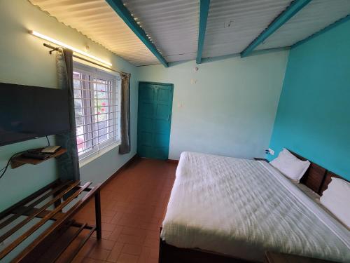 Schlafzimmer mit einem Bett und einem Flachbild-TV in der Unterkunft REFLECTIONS Guest House in Udagamandalam