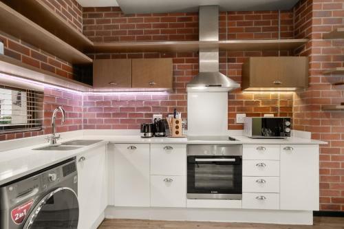 a kitchen with white cabinets and a brick wall at Easy Stay - The Vantage Rosebank in Johannesburg