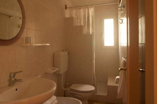 La salle de bains blanche est pourvue d'un lavabo et de toilettes. dans l'établissement Agriturismo Don Lucifero, à Orosei