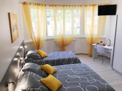 2 camas en una habitación con cortinas amarillas en Appartement Le Solea 100m2 climatisé parking proche Sanctuaires en Lourdes