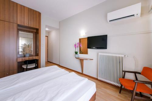 1 dormitorio con 1 cama blanca y TV en Hotel Cronos, en Árta