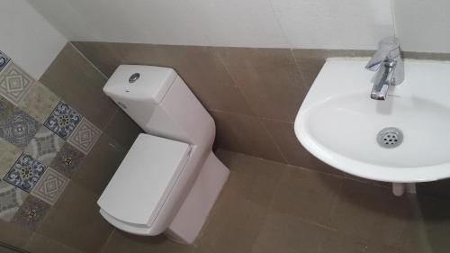 a bathroom with a white toilet and a sink at REFLECTIONS Guest House in Ooty