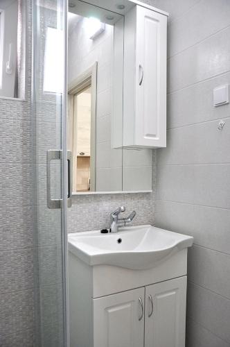 a white bathroom with a sink and a mirror at Old marine house in Tivat